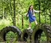 Girl playing on large rubber tires in Park woodland