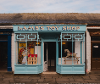 A rocking horse, a toy house and boat shown in the front windows of the toy shop.