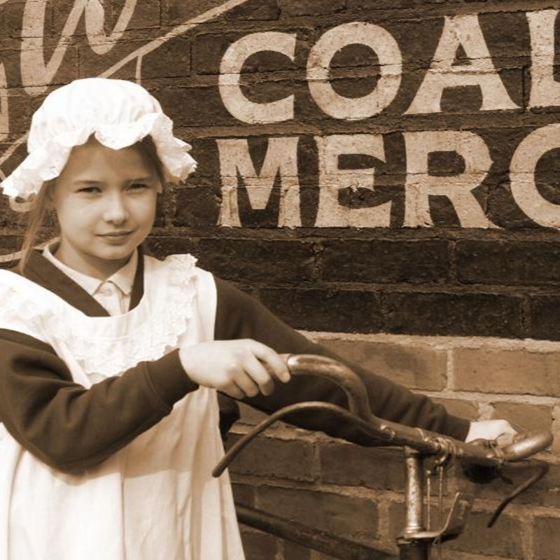 Girl Wearing Victorian Costume Holding An Old Fashioned Bike