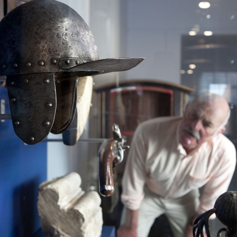 Visitor Looking At Items On Display In A Case Including A Pistol And Viking Helmet