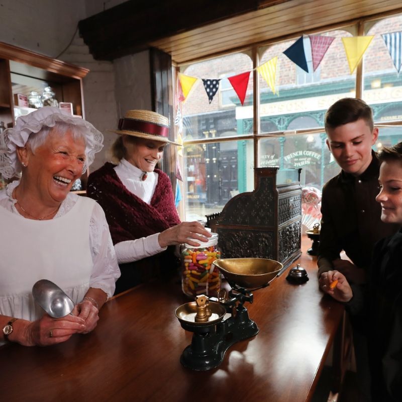 Young Boys Being Served Sweets By Two Victorian Ladies In The Old Fashioned Sweet Shop